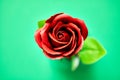 Minimalistic of an artificial red rose image photographed in studio isolated on green