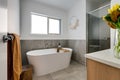 Minimalistic bathroom interior with a bathtub, glass shower doors and a towel on a towel rack