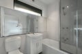 Minimalistic bathroom interior in white and gray tones with a walk-in shower, toilet, and a sink