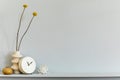 Minimalistic composition on the shelf with dried flower in design vase, white clock and accessories. Grey wall. Copy space