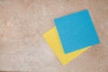 A minimalistic composition of yellow and blue kitchen rags lying on a textured tabletop