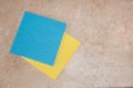 A minimalistic composition of yellow and blue kitchen rags lying on a textured tabletop