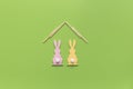 Minimalistic creative Easter concept. Two Easter bunnies under roof on green. Easter holiday at home. greeting card