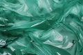 Minimalistic green texture of transparent wrinkled plastic. Crumpled wrinkled plastic cellophane. Reflects light and shadow on the