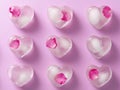 Minimalistic heart shaped ice cubes with rose petals on pink background Royalty Free Stock Photo