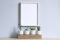 Minimalistic home interior with mock up photo frame on the brown table with composition of cacti and succulents. Royalty Free Stock Photo