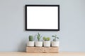 Minimalistic home interior with mock up photo frame on the brown table with composition of cacti and succulents. Royalty Free Stock Photo