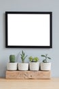 Minimalistic home interior with mock up photo frame on the brown table with composition of cacti and succulents. Royalty Free Stock Photo