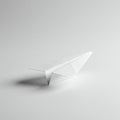 A minimalistic image features a white paper airplane resting on a smooth, light gray Royalty Free Stock Photo