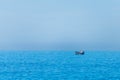 Minimalistic image of the sea with a fishing boat. Blue sea water and clear sky