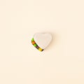 Minimalistic isolated heart shaped white bowl with colorful candies on bright background.