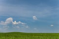 Minimalistic Landscape With Green Field And Blue Sky With Small Clouds