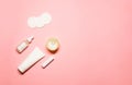 Minimalistic layout with hand cream in a white tube, essential oil, lip balm, cotton pads, and a candle on a pastel pink Royalty Free Stock Photo