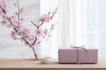 Minimalistic lilac gift packaging and a glass vase with cherry blossom branches. Place for text. Royalty Free Stock Photo