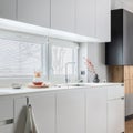 Minimalistic and modern white kitchen interior with furniture and kitchen accessories in stylish home decor. Windows. Details.