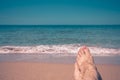 Minimalistic photo of woman`s feet on the beach overlooking the sea. Royalty Free Stock Photo