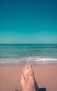 Minimalistic photo of woman`s feet on the beach overlooking the sea.