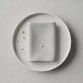 A minimalistic setup features a round white ceramic plate on a light gray, textured Royalty Free Stock Photo