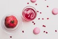 Minimalistic still life with pomegranate fruit and pomegranate juice in a glass glass with an ice cube in the shape of a heart on