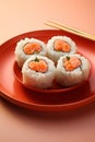 Minimalistic style sushi pieces on red dish with chopsticks, close-up shot against peach background Royalty Free Stock Photo