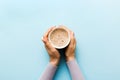 Minimalistic style woman hand holding a cup of coffee on Colored background. Flat lay, top view cappuccino cup. Empty Royalty Free Stock Photo