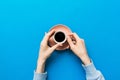 Minimalistic style woman hand holding a cup of coffee on Colored background. Flat lay, top view cappuccino cup. Empty Royalty Free Stock Photo