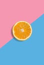 Minimalistic summer fruit tropical composition. Half of juicy fresh orange on light pastel pink and blue background. Citrus fruit Royalty Free Stock Photo