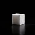Minimalistic white sugar cube on a dark reflective surface