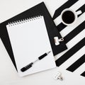 Minimalistic workspace with book, notebook, pencil, cup of coffee on striped black and white background. Flat lay style Top view