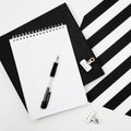 Minimalistic workspace with book, notebook, pencil on striped black and white background. Flat lay style Top view Royalty Free Stock Photo