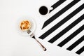 Minimalistic workspace with cup of coffee, bakery, isolated on striped black and white background. Flat lay style Top view. Royalty Free Stock Photo