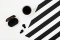 Minimalistic workspace with cup of coffee, wireless earphones on striped black and white background. Flat lay style Top view. Royalty Free Stock Photo