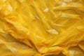 Minimalistic yellow texture of transparent wrinkled plastic. Crumpled wrinkled plastic cellophane. Reflects light and shadow on