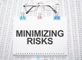 minimizing risks text written on paper with pen and glasses