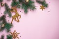Christmas composition. Christmas tree branches, with New Year`s gold ornaments and multi-colored sweets on a pink background.