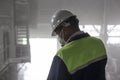 Mining engineer in white helmet and respirator inspects dusty dirty workshop