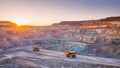 A mining site with large dump trucks under a setting sun Royalty Free Stock Photo