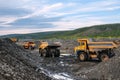 Mining trucks are queuing, in the background a wheel loader is loading mountain soil into the bodies of these trucks Royalty Free Stock Photo