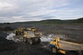 Mining trucks are queuing, in the background a wheel loader is loading mountain soil into the bodies of these trucks Royalty Free Stock Photo