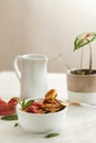 Minipancakes breakfast - white bowl with strawberries and pancakes, mik jar, honey, fresh mint and house plant. Lifestyle morning