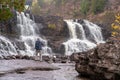 Male photographer uses a tripod to take long exposure photos of Gooseberry Falls waterfall on a