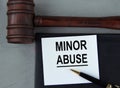 MINOR ABUSE - words on a white sheet with leather notebooks, a judge\'s hammer and a pen