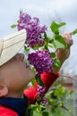 A minor child sniffs a bouquet of lilacs.