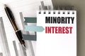MINORITY INTEREST text on notebook with chart on gray background Royalty Free Stock Photo