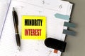 MINORITY INTEREST text sticky on dairy on gray background Royalty Free Stock Photo