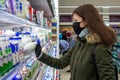 MINSK, BELARUS - April 27, 2020: Woman in a protective mask and gloves holding milk bottle in grocery store during epidemic.