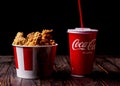 Minsk, Belarus - December 03, 2021: black background, night. Lots of hot wings or KFC chicken pieces. a glass of coca-cola