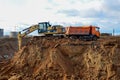 Excavator CATERPILLAR 320L load the sand to the heavy dump truck MAZ on construction site