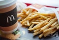 Minsk, Belarus, February 18, 2018: Paper cup of coffee with McDonald`s logo and French fries in McDonald`s Restaurant