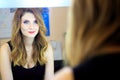 beautiful red-haired girl doing makeup in front of the mirror Royalty Free Stock Photo